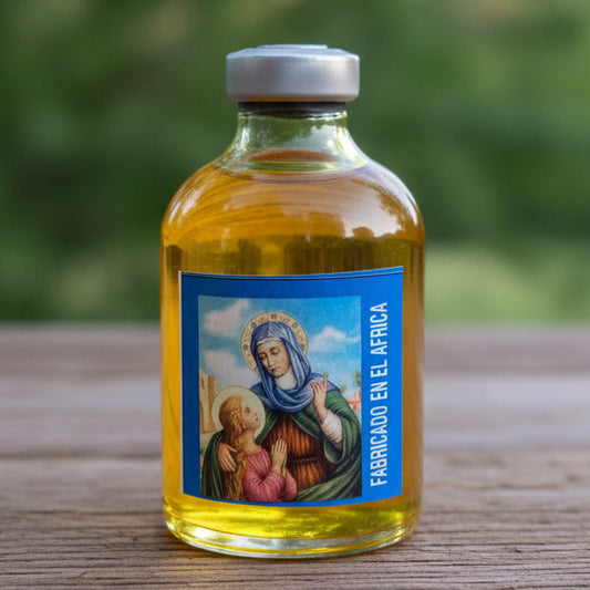 A small glass bottle filled with golden yellow liquid and topped with a silver cap, placed on a white stone slab. The bottle has a blue label with a religious illustration and the text 'TANTO MONTA EN EL AFIRO'.